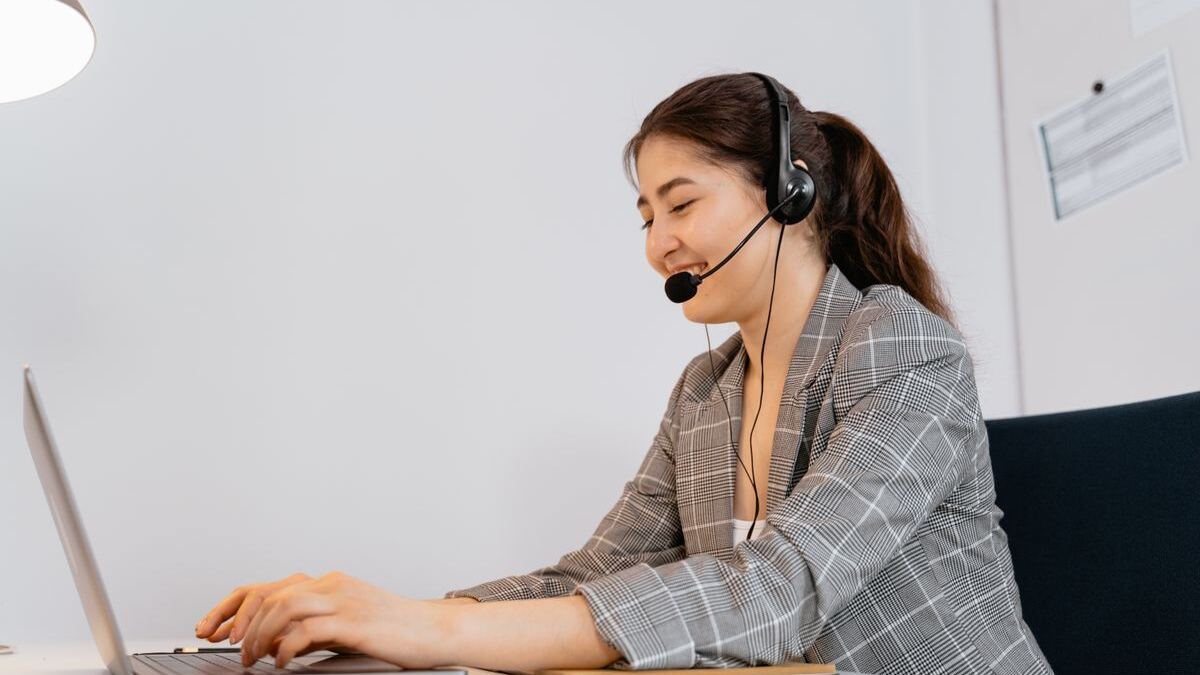 Assistante virtuelle souriante avec un casque, travaillant sur son ordinateur portable